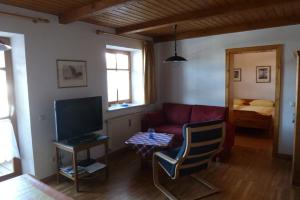 a living room with a red couch and a television at Appartementhaus Osserblick in Lohberg