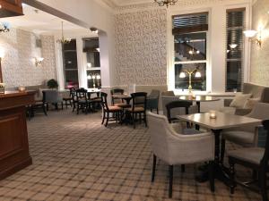 um restaurante com mesas, cadeiras e janelas em The Clarendon Hotel em Morecambe