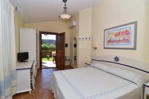 a bedroom with a white bed and white walls at Li Suari Club Village in San Teodoro