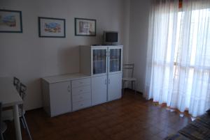 Cette chambre comprend une armoire blanche avec une télévision. dans l'établissement Condominio San Michele, à Bibione