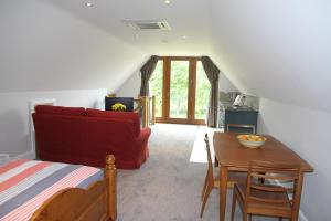 a living room with a red couch and a table at Superb Stokesby Barn Apartment - Norfolk Broads & Norwich in Stokesby
