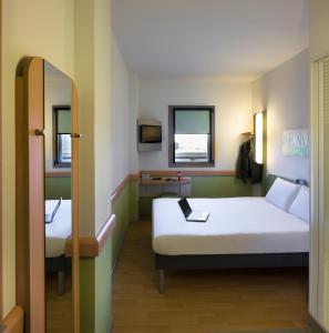 マドリードにあるイビス バジェット マドリード セントロ ラス ベンタスのベッド2台と鏡が備わる客室です。