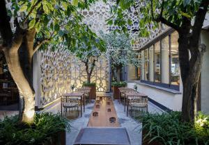 a row of tables and chairs with trees in a building at EME Catedral Mercer Hotel in Seville
