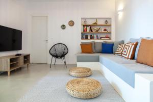 a living room with a couch and a tv at Galini Villas in Mikros Gialos