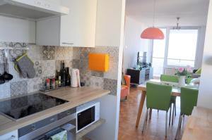 a kitchen with white cabinets and green chairs in a room at Razgled/The View in Koper