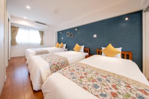 three beds in a room with a blue wall at Hotel Haabesu Okinawa in Urasoe
