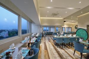 a restaurant with tables and chairs and large windows at Effotel by Sayaji Vadodara in Vadodara
