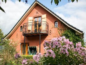 a red brick house with a balcony and flowers at Ferienhof Hedwigsruh in Stadum