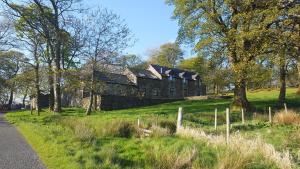 une ancienne maison en pierre sur une colline avec une route dans l'établissement B&B Drum Farm, à Stirling