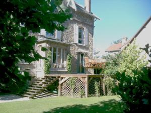 una grande casa in pietra con un ponte in legno di fronte di Les Chambres de LOUIS a Le Chesnay