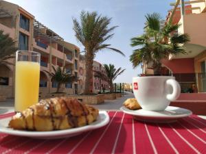 a table with a plate of food and a cup of orange juice at Aparthotel Por do Sol in Sal Rei
