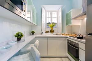 a kitchen with white cabinets and green accents at Genteel Home Pajaritos in Seville