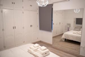 Schlafzimmer mit weißen Schränken, einem Bett und einem Spiegel in der Unterkunft Apartamento turístico Calle San Basilio 6 patios in Córdoba