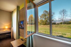 Habitación con ventanas, escritorio y mesa. en Hotel Lučivná, en Lučivná