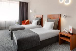エカテリンブルクにあるモスコフスカヤ ゴルカ バイ ウスタ ホテルズのベッド2台とテーブルが備わるホテルルームです。
