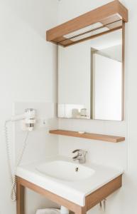 a bathroom with a sink and a mirror at Terres de France - Appart'Hotel Quimper Bretagne in Quimper