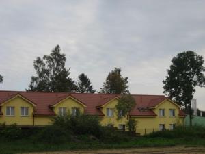 una casa amarilla con techo rojo en Ośrodek Wczasowo - Kolonijny Słoneczko, en Łeba