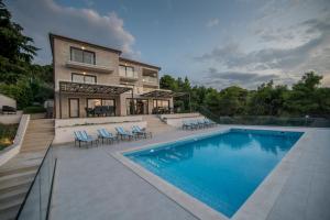 uma casa com piscina em frente a uma casa em Villa D em Postira