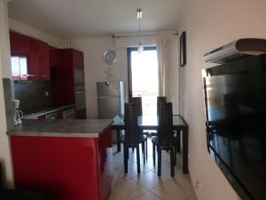 eine Küche mit roten Schränken sowie einem Tisch und Stühlen in der Unterkunft Appartement Villeneuve Loubet in Villeneuve-Loubet