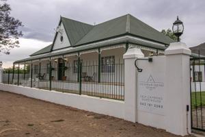 a building with a fence and a sign in front of it at Victorian Square Guesthouse in Graaff-Reinet