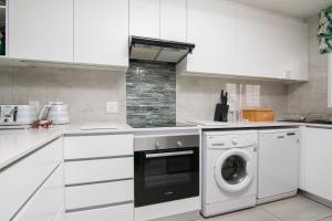 a white kitchen with a washing machine in it at Le Paradis 23 in Ballito