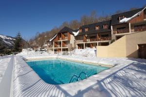 a swimming pool covered in snow in front of a building at Résidence Néméa La Soulane in Loudenvielle