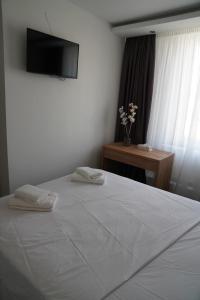 um quarto com uma cama branca e uma televisão na parede em Millrather Brauhaus em Erkrath