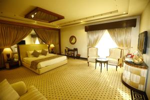a hotel room with a bed and a table and chairs at Bahria Grand Hotel & Resort in Lahore