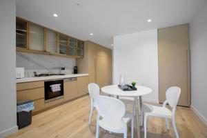 a kitchen with a white table and white chairs at Warm Nest Central Location@Collins in Melbourne