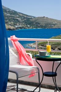 a table and chair with a drink on a balcony at Elpida Andros in Batsi