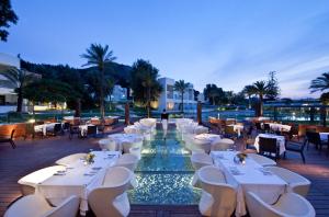 a restaurant with white tables and chairs next to a pool at ABAV2 Suites by Rodos Palace in Ixia