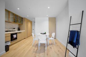 uma cozinha com uma mesa branca e cadeiras brancas em Warm Nest Central Location@Collins em Melbourne
