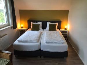 two beds in a small room with two lamps at B&B de Rivierduin in Hattem