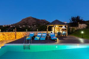 a swimming pool with chairs and a gazebo at Ekaterini Vip Villa in Plaka