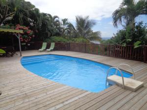 una piscina en una terraza de madera con una valla de madera en Villa Fleur de Lune, en Bouillante