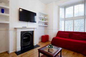 a living room with a red couch and a fireplace at Arsenal 123 in London