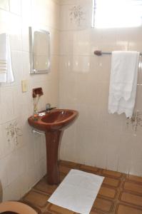 a bathroom with a wooden sink and a shower at Hotel Caçula in Londrina