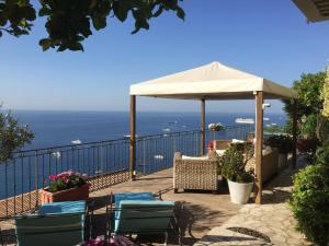 a patio with chairs and an umbrella and the ocean at Chambre d'hôtes de charme La Belle Vue in Roquebrune-Cap-Martin