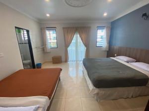 a bedroom with two beds and two windows at HILLVIEW HOMESTAY in Tanah Rata