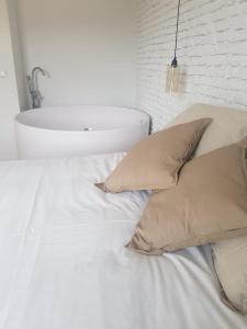 uma cama branca com almofadas e um lavatório num quarto em Dos Alas Rojas, casa con jacuzzi para dos personas em Mélida