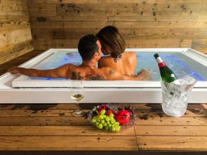 a man and woman in a hot tub with a bottle of wine at Residence Lake Como in Colico