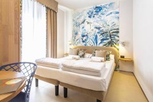 1 dormitorio con 1 cama con una pintura en la pared en Costa Rica Bibione Aparthotel, en Bibione