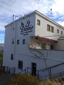 a white building with a sign on the side of it at Hostal El Desvío in Sierra Nevada