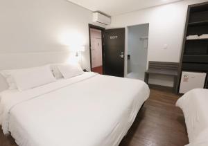 una camera d'albergo con un grande letto bianco e una sedia di Fratele Business Hotel a Patos de Minas