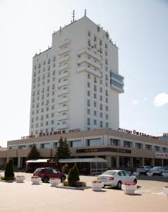 un gran edificio blanco con coches aparcados en un aparcamiento en Kolomna Hotel, en Kolomna