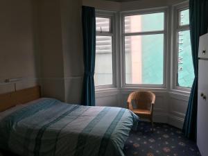 ein Schlafzimmer mit einem Bett, einem Fenster und einem Stuhl in der Unterkunft Walford Hotel in Blackpool