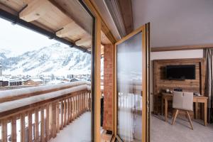 hotel & chalet madlochBlick في ليش ام ارلبرغ: غرفة مع شرفة مع مكتب وتلفزيون