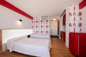 1 dormitorio con cama blanca y nevera roja en Apartamentos La Kiki, en Bahía de San Antonio