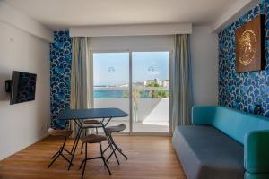 sala de estar con sofá azul, mesa y ventana en Apartamentos La Kiki, en Bahía de San Antonio