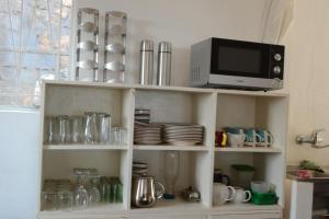 a kitchen shelf with a microwave and a tv at Kuwona Cottage in Senga